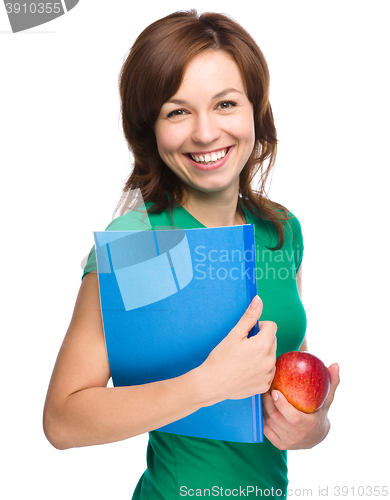 Image of Young student girl is holding book and apple