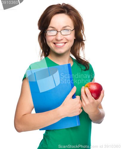 Image of Young student girl is holding book and apple