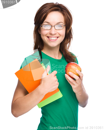 Image of Young student girl is holding book and apple