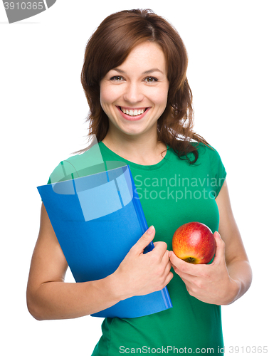 Image of Young student girl is holding book and apple