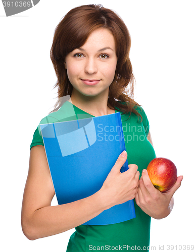 Image of Young student girl is holding book and apple