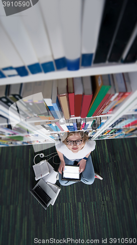 Image of female student study in library, using tablet and searching for 