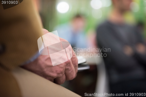 Image of Closeup of mature hands holding tablet.