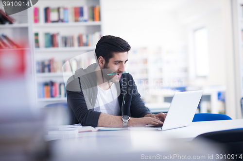 Image of student in school library using laptop for research