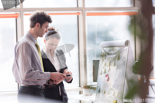 Image of young couple working on flip board at office