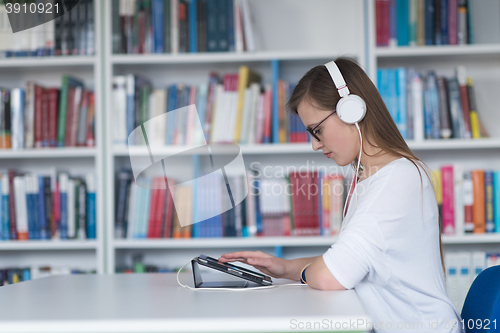 Image of female student study in library, using tablet and searching for 