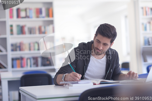 Image of student in school library using laptop for research