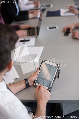 Image of close up of  businessman hands  using tablet on meeting