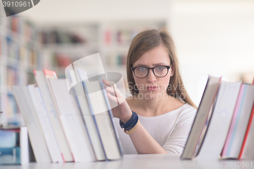 Image of portrait of famale student selecting book to read in library