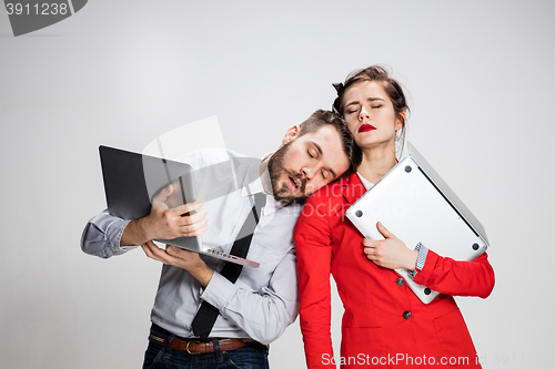 Image of The young businessman and businesswoman with laptops on gray background