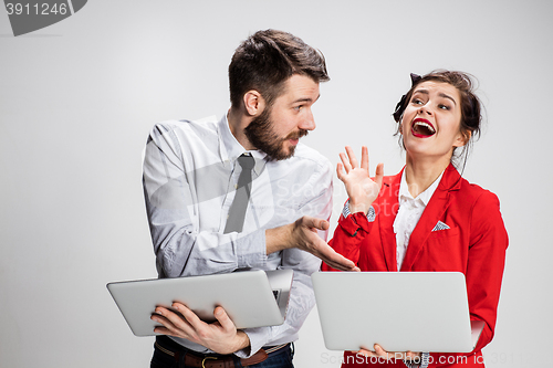 Image of The young businessman and businesswoman with laptops communicating on gray background