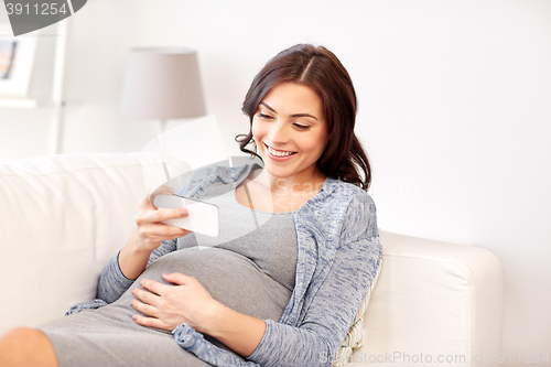 Image of happy pregnant woman with smartphone at home
