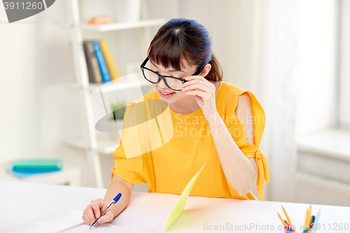 Image of happy asian young woman student learning at home