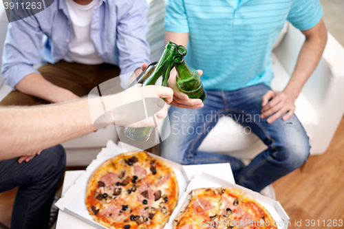 Image of close up of male hands with beer and pizza at home