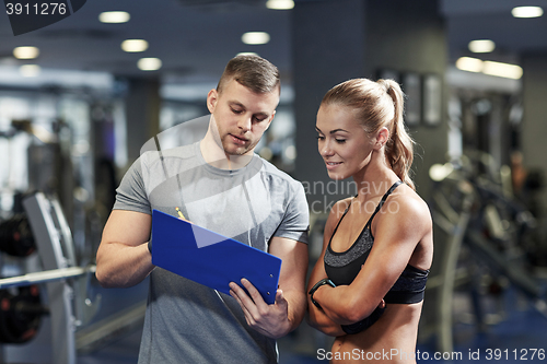 Image of smiling young woman with personal trainer in gym