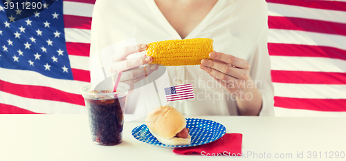 Image of woman hands holding corn with hot dog and cola