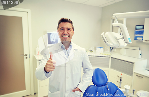 Image of happy male dentist showing thumbs up at clinic