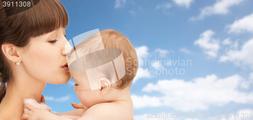 Image of happy mother kissing baby boy over sky background