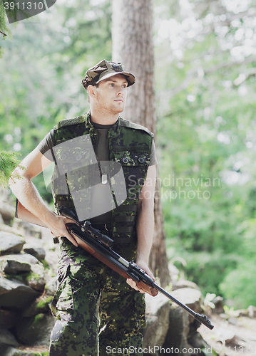 Image of young soldier or hunter with gun in forest