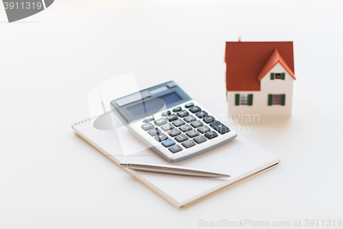 Image of close up of home model, calculator and notebook