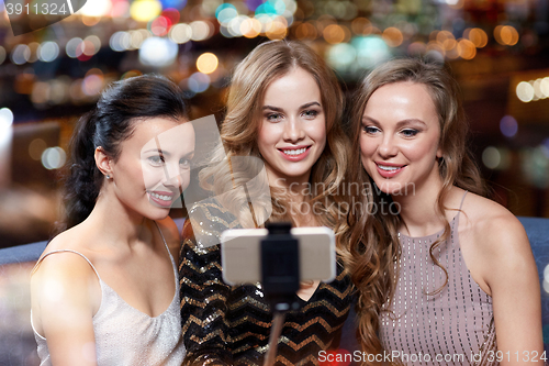 Image of women with smartphone selfie stick at night club