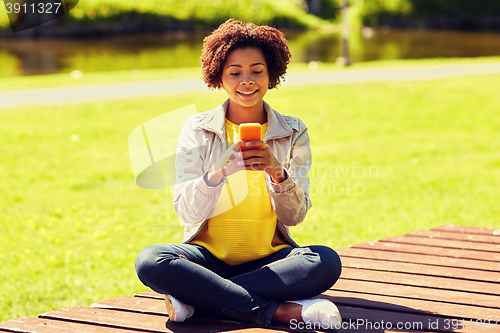 Image of happy african young woman messaging on smartphone