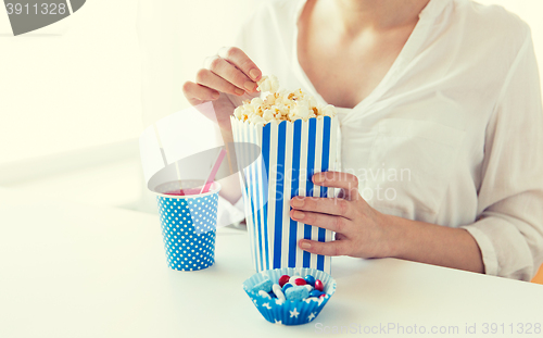 Image of woman eating popcorn with drink and candies