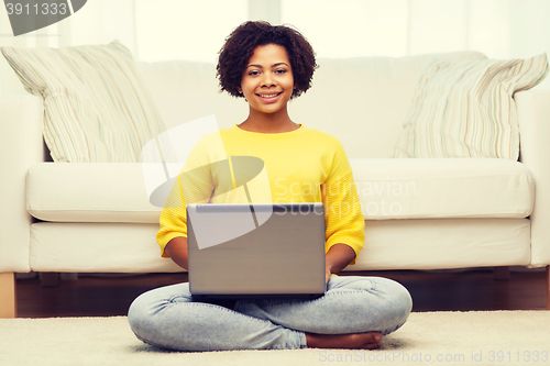 Image of happy african american woman with laptop at home