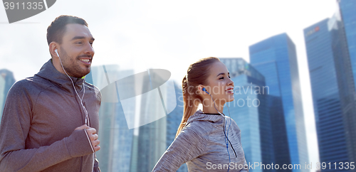 Image of happy couple with earphones running in city