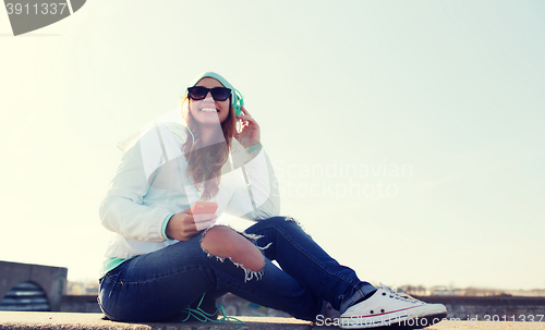 Image of happy young woman with smartphone and headphones