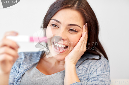 Image of happy woman looking at home pregnancy test