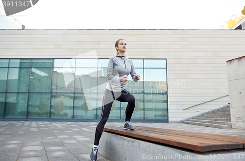 Image of woman making step exercise on city street bench