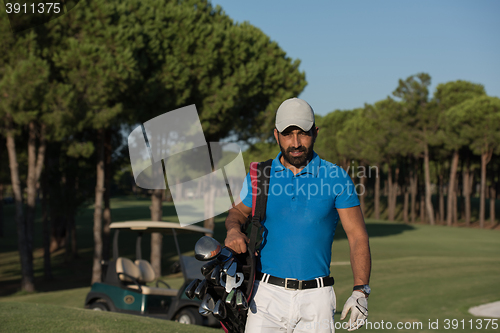 Image of golfer  walking and carrying golf  bag