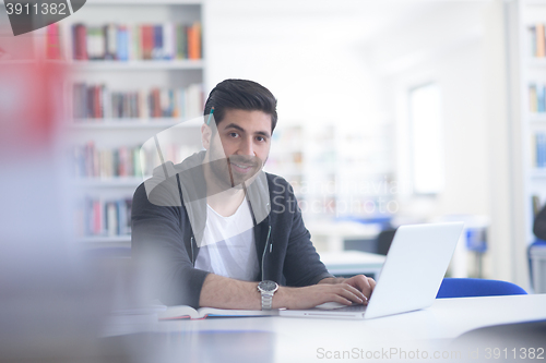 Image of student in school library using laptop for research