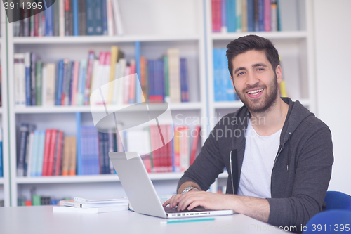 Image of student in school library using laptop for research