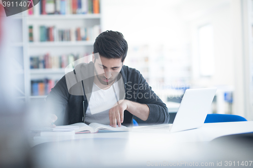 Image of student in school library using laptop for research