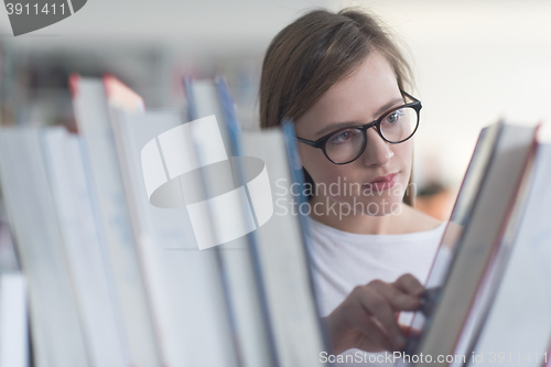 Image of portrait of famale student selecting book to read in library