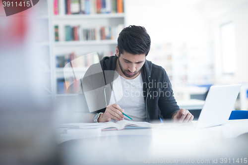 Image of student in school library using laptop for research