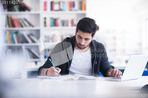 Image of student in school library using laptop for research