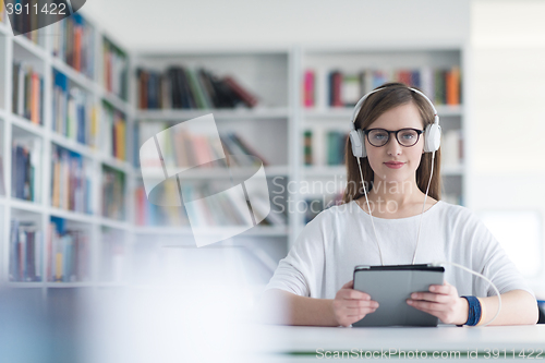 Image of female student study in library, using tablet and searching for 