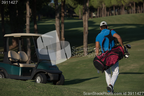 Image of golfer  walking and carrying golf  bag