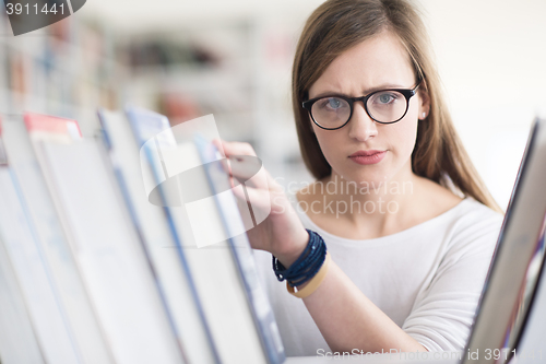 Image of portrait of famale student selecting book to read in library