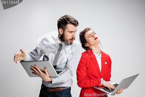 Image of The young businessman and businesswoman with laptops on gray background