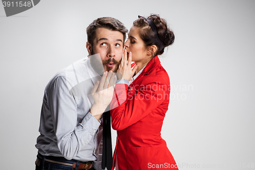 Image of Young man telling gossips to his woman colleague at the office