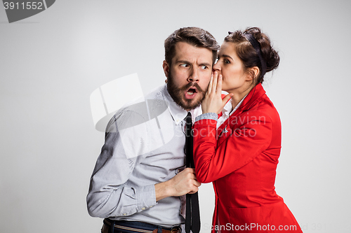 Image of Young man telling gossips to his woman colleague at the office