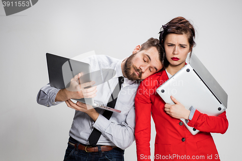 Image of The young businessman and businesswoman with laptops on gray background