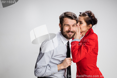 Image of Young man telling gossips to his woman colleague at the office