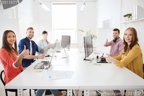 Image of creative team with computers showing thumbs up