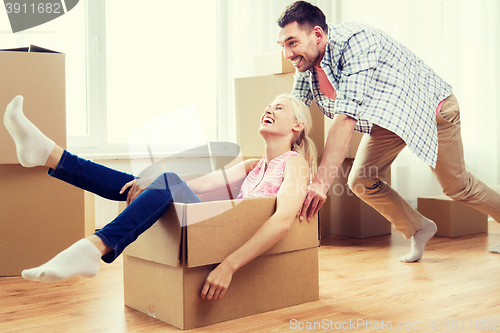 Image of couple with cardboard boxes having fun at new home