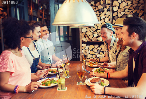 Image of happy friends eating and drinking at bar or pub